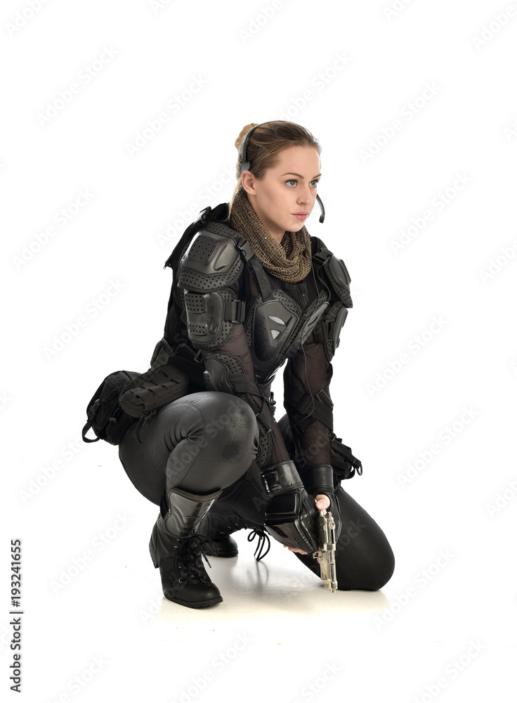 full length portrait of female wearing black tactical armour, crouching pose holding a weapon, isolated on white studio background. full length portrait of female wearing black tactical armour, crouching pose holding a weapon, isolated on white studio background.