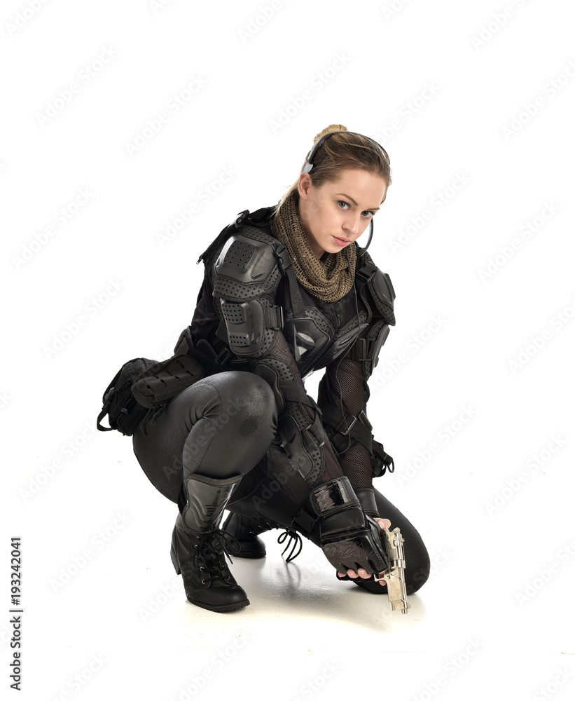 full length portrait of female wearing black tactical armour, crouching pose holding a weapon, isolated on white studio background. full length portrait of female wearing black tactical armour, crouching pose holding a weapon, isolated on white studio background.