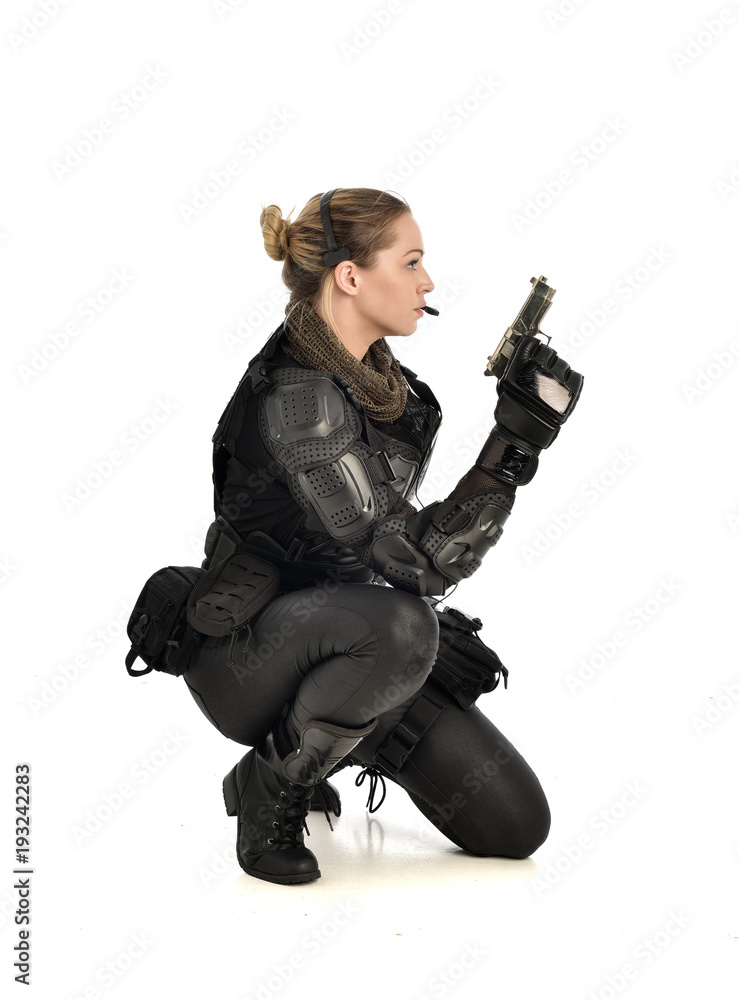 full length portrait of female wearing black tactical armour, crouching pose holding a weapon, isolated on white studio background. full length portrait of female wearing black tactical armour, crouching pose holding a weapon, isolated on white studio background.