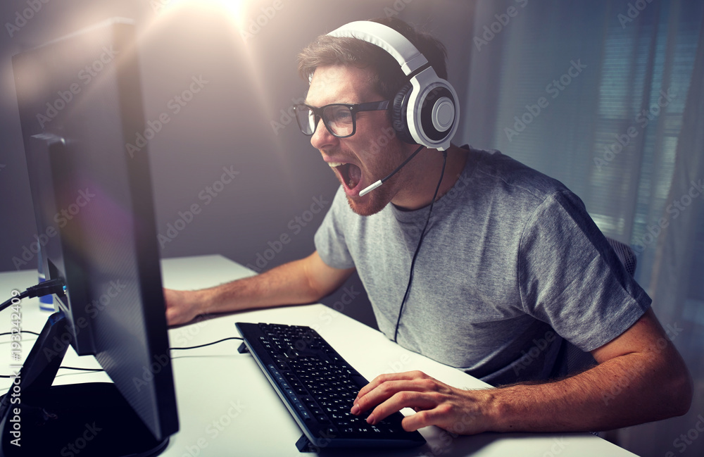 man in headset playing computer video game at home man in headset playing computer video game at home