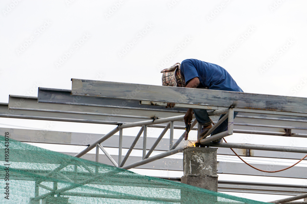 A construction workers installing beam formwork. Formwork is located at the high level that requires the workers to use scaffolding. A construction workers installing beam formwork. Formwork is located at the high level that requires the workers to use scaffolding.