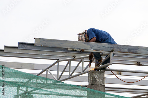 A construction workers installing beam formwork. Formwork is located at the high level that requires the workers to use scaffolding.