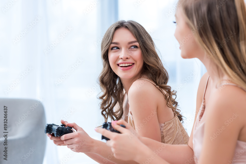 attractive smiling girls playing with joysticks at pajama party attractive smiling girls playing with joysticks at pajama party