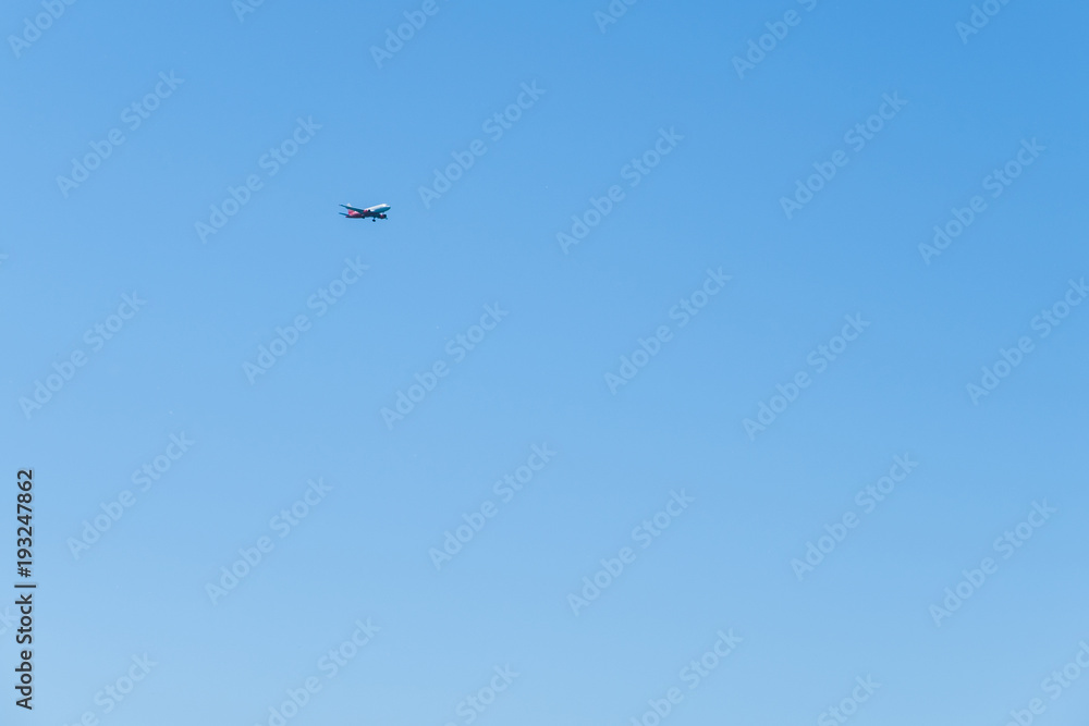 Red-and-white plane flying through the sky to land. Red-and-white plane flying through the sky to land.