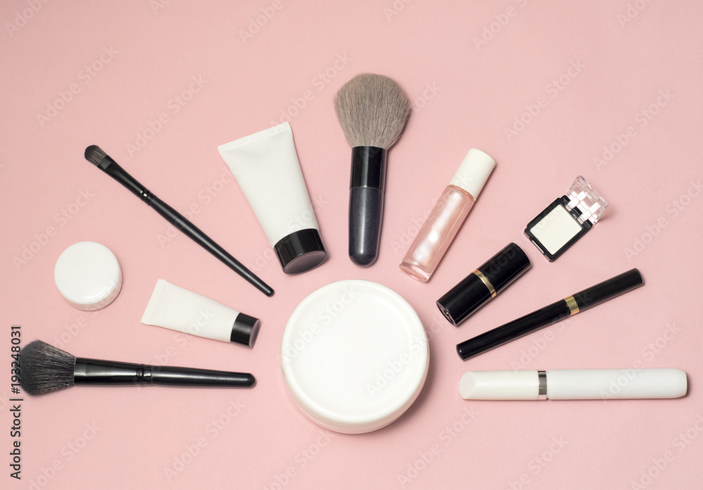 Set of makeup cosmetics, brushes, concealer and other essentials on pink background Set of makeup cosmetics, brushes, concealer and other essentials on pink background