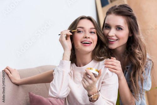 beautiful smiling young women applying makeup at home