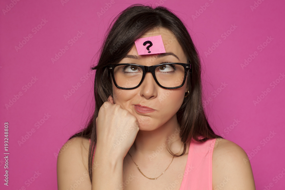 Puzzled young woman with question mark on her foreead Puzzled young woman with question mark on her foreead
