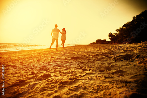 Summer golden sunset and two lovers on beach 
