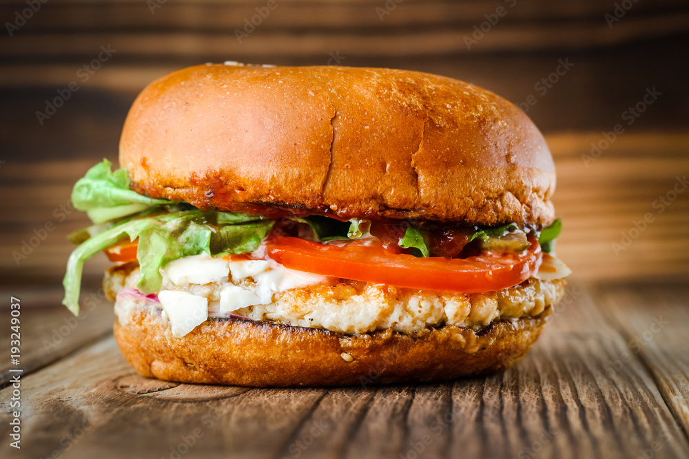burger with chicken cheese and sauce on wooden background. burger with chicken cheese and sauce on wooden background.