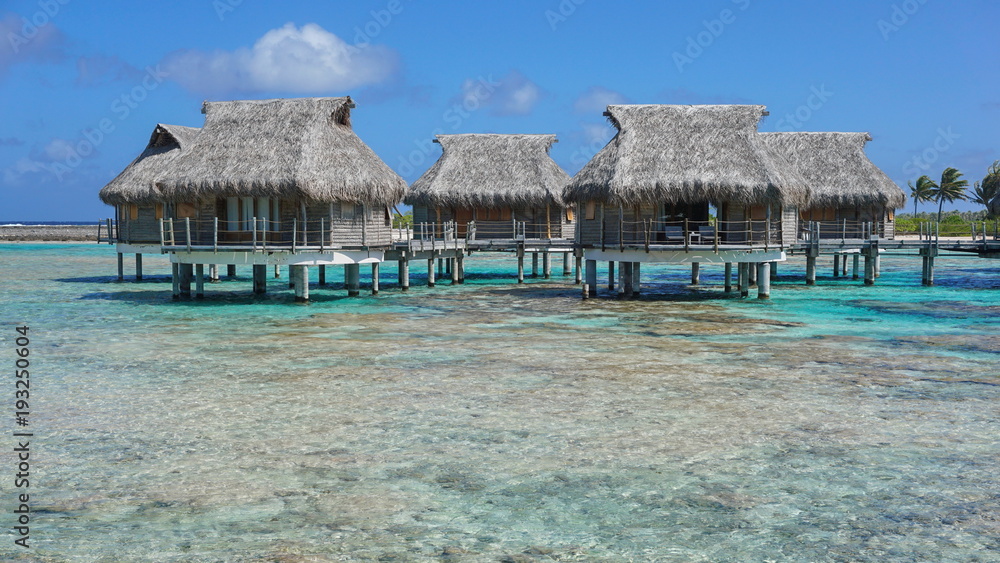 Tropical bungalows with thatched roof over the sea in the lagoon, Tikehau atoll, Tuamotus, French Polynesia, Pacific ocean, Oceania