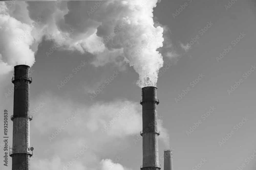 Factory chimneys smoke in cloudy sky