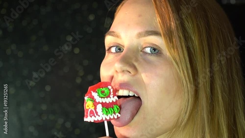 blonde woman licks a delicious sweet lollipop