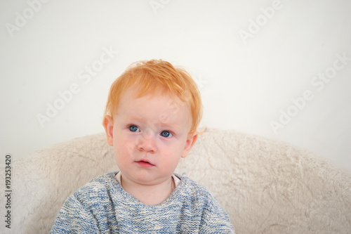 The boy looks up thoughtfully on the white background