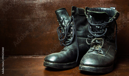 Old military boots against wooden background