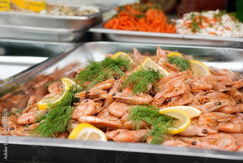 Ready-made, cooked prawns with greens and slices of lemon on a tray, Side view close-up.