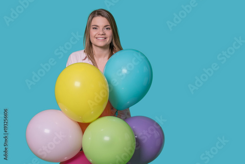 Beautiful young woman with balloons on isolated blue background