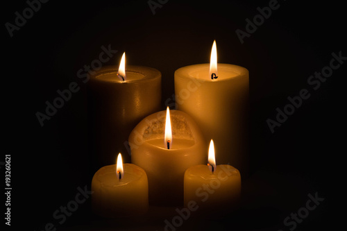 Set of three burning candles against a dark background