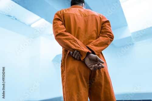 Canvas Print bottom view of prisoner in orange uniform standing in prison cell