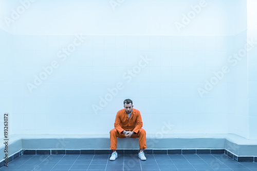 Fotografia prisoner sitting on bench in prison room