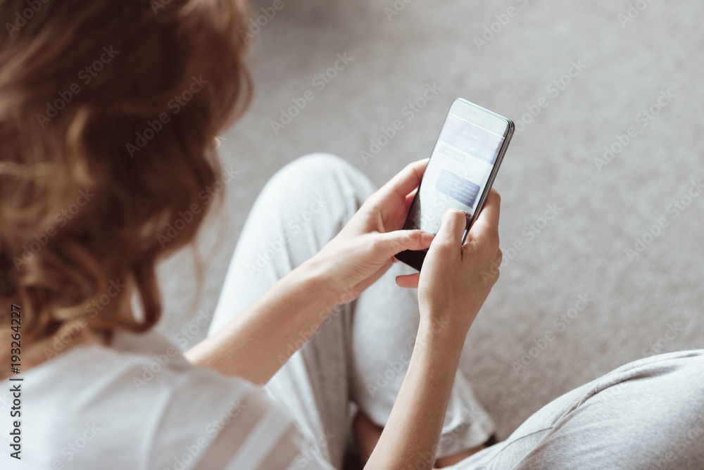 Good news. Selective focus on a screen of a smartphone held by a lady wearing pajamas sitting on the floor while reading a message. Good news. Selective focus on a screen of a smartphone held by a lady wearing pajamas sitting on the floor while reading a message.