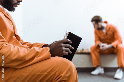Bild auf Leinwand cropped image of african american prisoner reading book