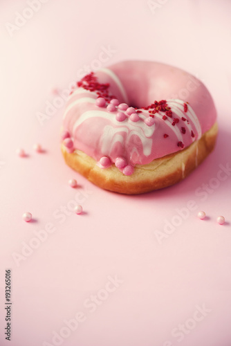 Sweet doughnut with pink icing on pastel background. Tasty donut on pink texture, copy space, top view