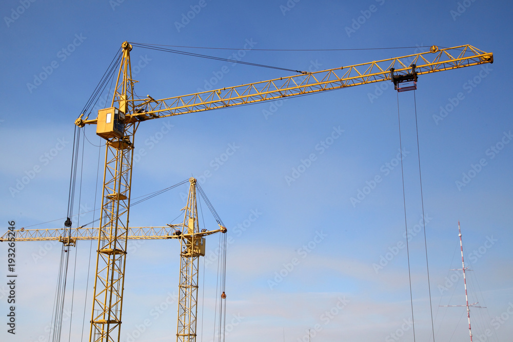 Working crane on the construction of the house. Construction site with cranes on sky background. 