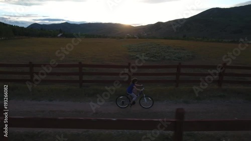 Girl riding bike on a country road at sunset.