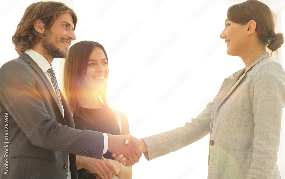 Businesspeople  shaking hands against room with large window loo