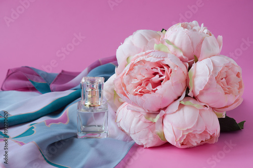 Bouquet of peonies and perfume on pink background