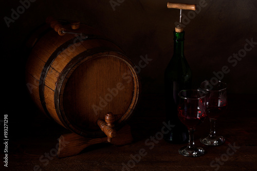 a small wooden wine bar, barrel on the legs and a wooden crane on a wooden background with a glass of wine and bottle of wine