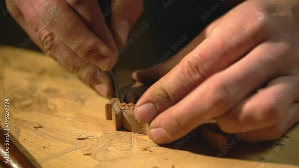 Closeup view of woodman working in craft studio, and carving patterns on small wooden material, with cutter slow motion Closeup view of woodman working in craft studio, and carving patterns on small wooden material, with cutter slow motion