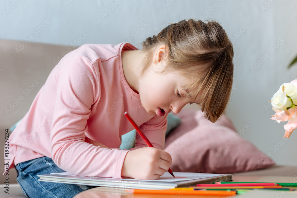 Child with down syndrome enthusiastically drawing with colorful pencils Child with down syndrome enthusiastically drawing with colorful pencils