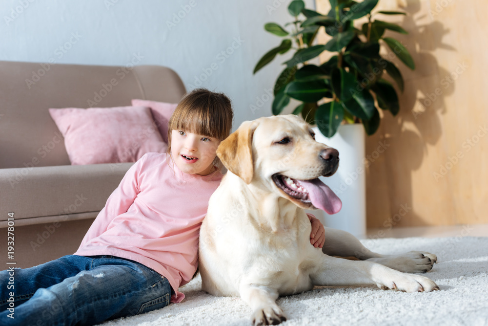 Child with down syndrome hugging Labrador retriever on the floor Child with down syndrome hugging Labrador retriever on the floor