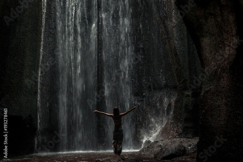 Uoung woman backpacker looking at the waterfall in jungles. Ecotourism concept image travel girl. Bali island, Indonesia.