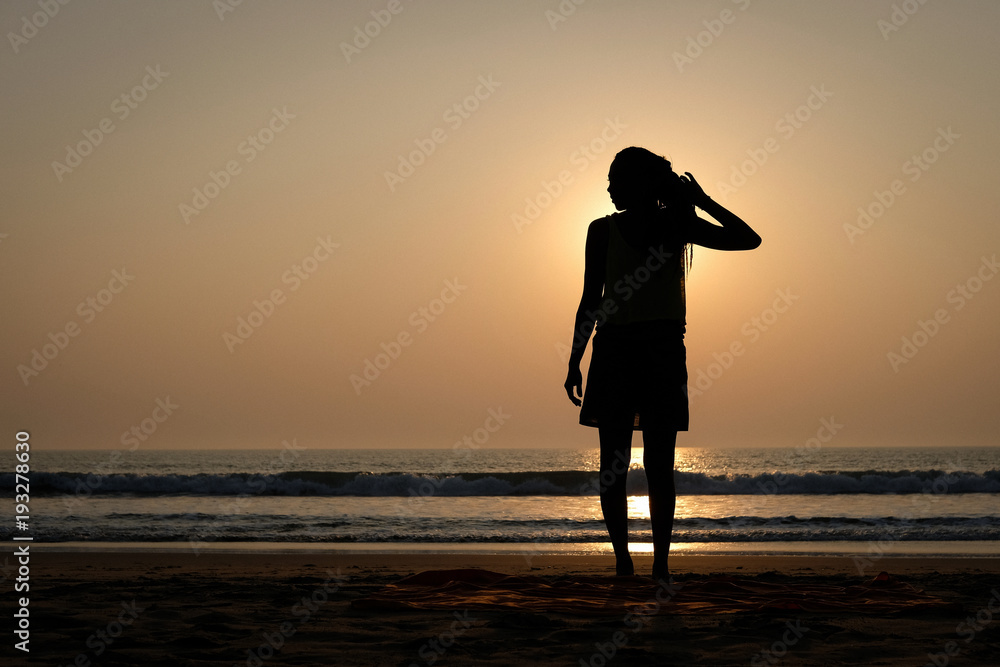 Woman's silhouette on the beach at sunset