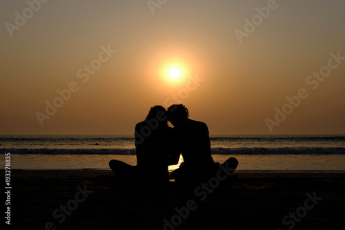 Couple's silhouette hugging on the beach at sunset