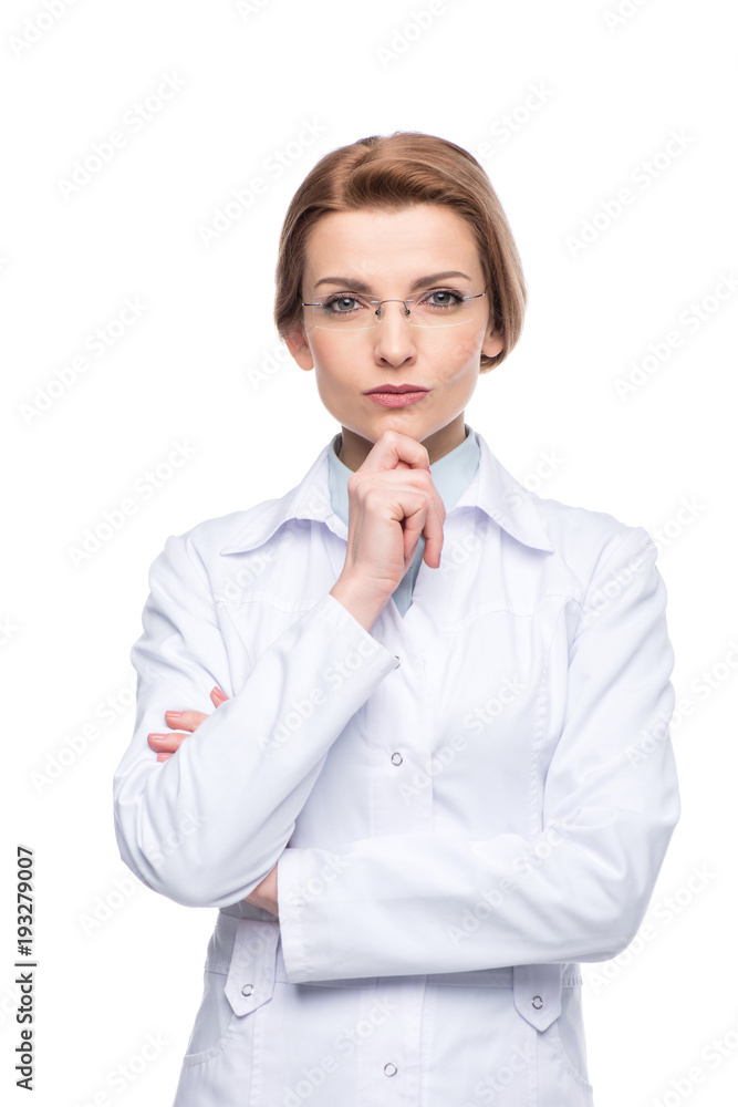 Young smiling female doctor wearing glasses with hand on chin isolated on white Young smiling female doctor wearing glasses with hand on chin isolated on white