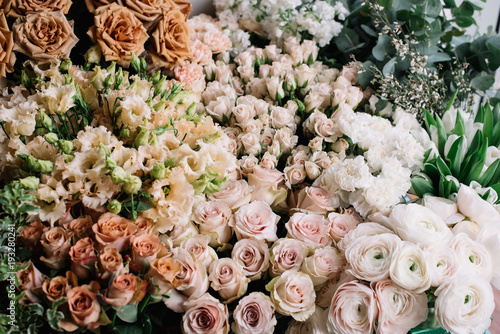A lot of fresh blossoming flowers (roses, peonies, ranunculus, carnations, eucalyptus) in warm pastel colours at the florist shop © anastasianess