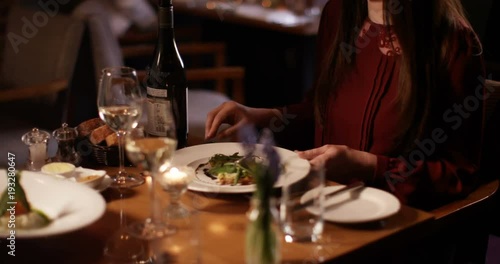 4K Waitress in a restaurant serves meals to happy young couple who raise their wine glasses for a toast