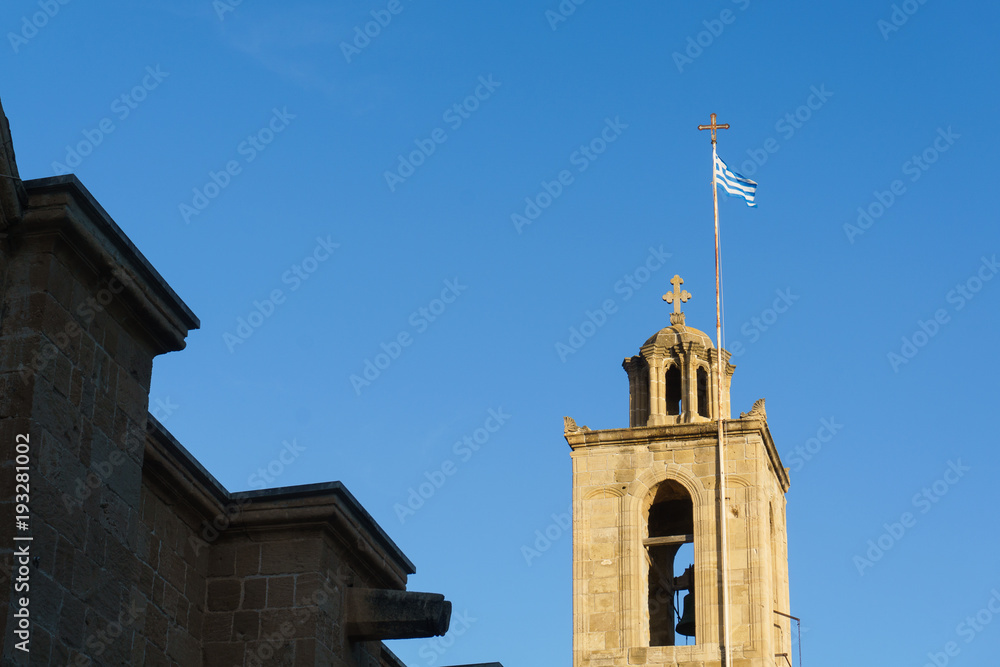 Photo of bell tower with Greek flag against blue sky