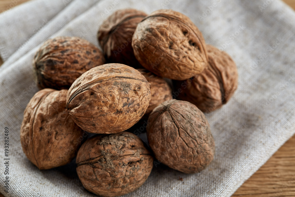 A stack of walnuts piled together and on rustic wooden background, shallow depth of field, selective focus A stack of walnuts piled together and on rustic wooden background, shallow depth of field, selective focus