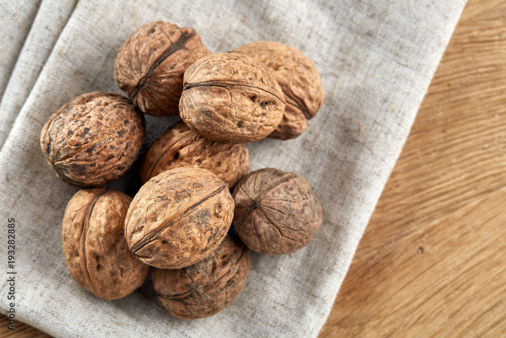 A stack of walnuts piled together and on rustic wooden background, shallow depth of field, selective focus A stack of walnuts piled together and on rustic wooden background, shallow depth of field, selective focus