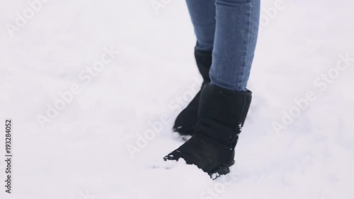 The legs of a young girl jumping to keep warm. The woman froze in a snow-covered winter park. photo