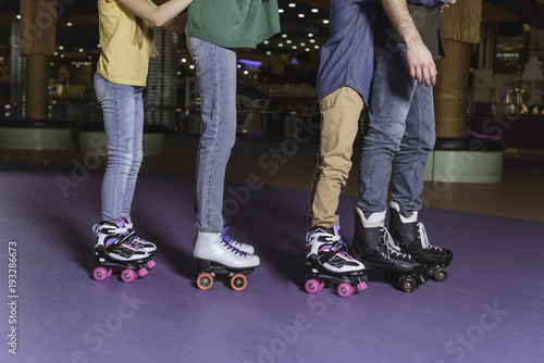 partial view of parents and kids skating on roller rink together