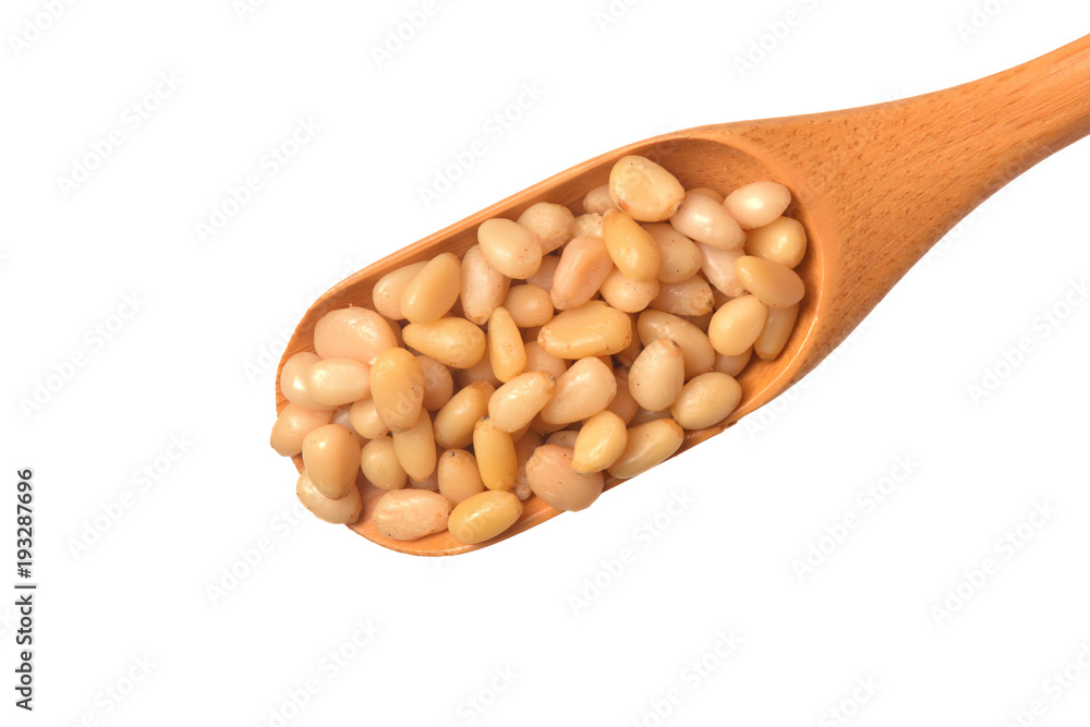 Pine nuts lie in a beautiful wooden spoon on a white background. Isolated Pine nuts lie in a beautiful wooden spoon on a white background. Isolated