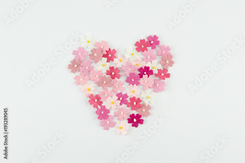 Heart shape made from pink paper flowers on white background 