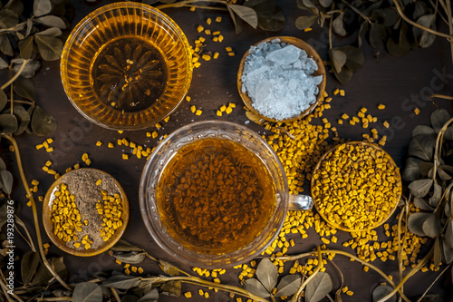 Tea of fenugreek/Fenugreek tea with honey,sugar fenugreek leaves and seeds on a wooden surface with dark Gothic colors.Benefits are include relief from anemia, loss of taste, fever, dandruff etc. photo