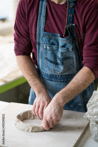 Ceramist Dressed in an Apron Working with Raw Clay in Bright Ceramic Workshop. photo