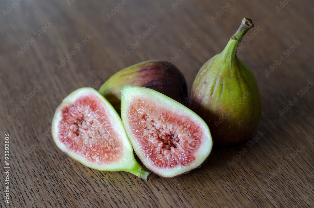 Close-up of fresh figs with one slised ripe fig on a wooden table background Close-up of fresh figs with one slised ripe fig on a wooden table background
